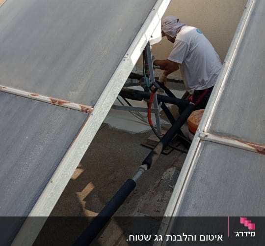 אדם עובד על איטום צינורות על גג